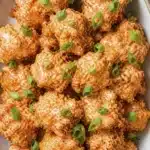 Crispy shrimp coated in creamy spicy sauce topped with chopped green onions and lime slices