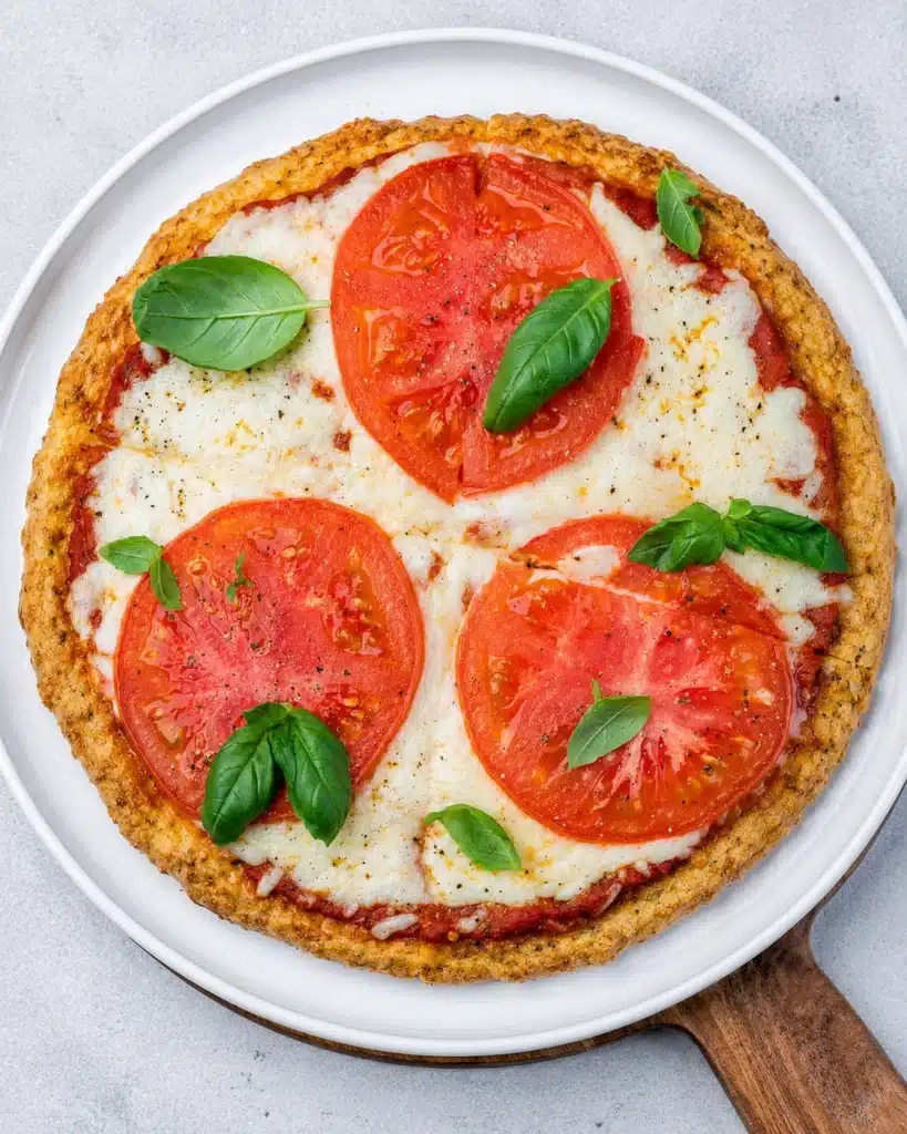 Top view of tomato basil pizza with evenly sliced portions and fresh green basil