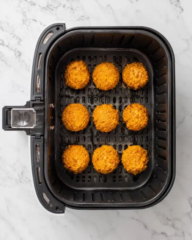 Top view of coated cheese balls arranged in an air fryer basket