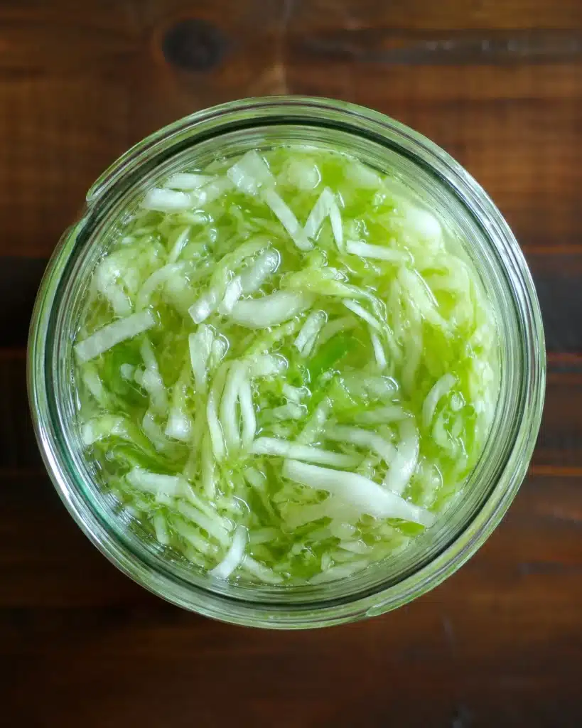top view of shredded cabbage soaking in liquid inside a glass jar during fermentation