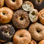Variety of golden bagels with sesame seeds, poppy seeds, and everything seasoning arranged together