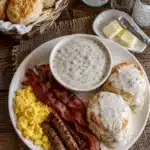 Southern style breakfast plate with biscuits gravy eggs and crispy beef bacon
