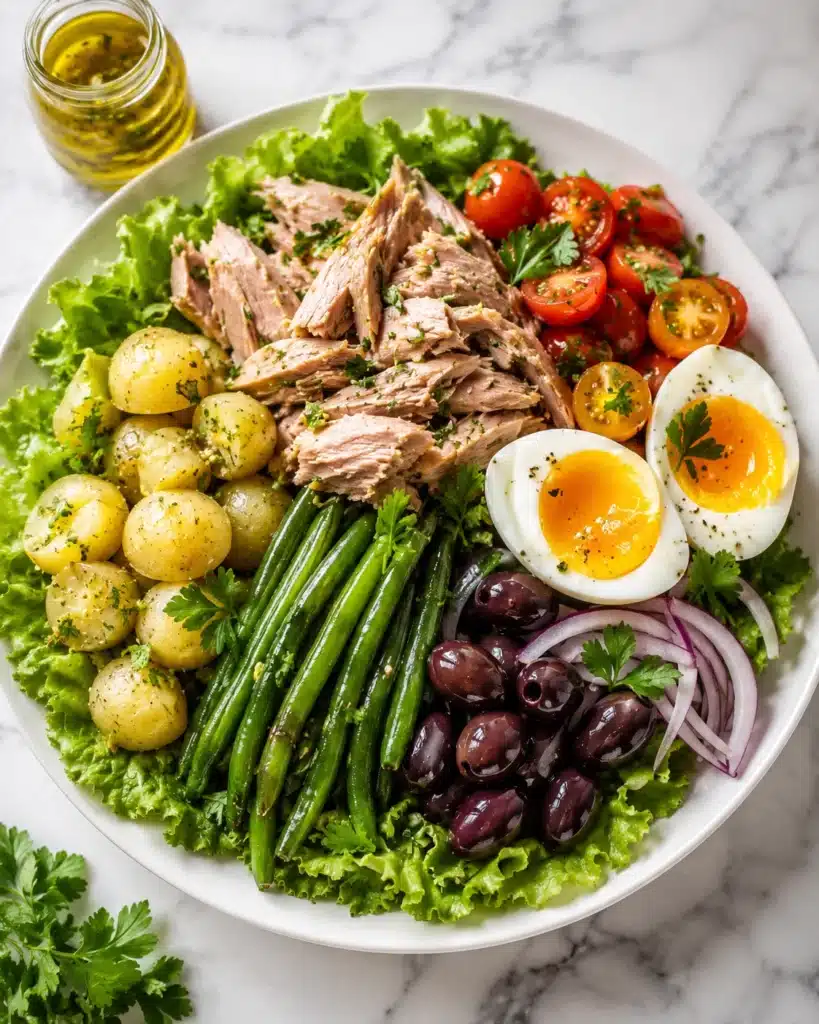 Composed salad with tuna, green beans, potatoes, eggs, and olives arranged neatly