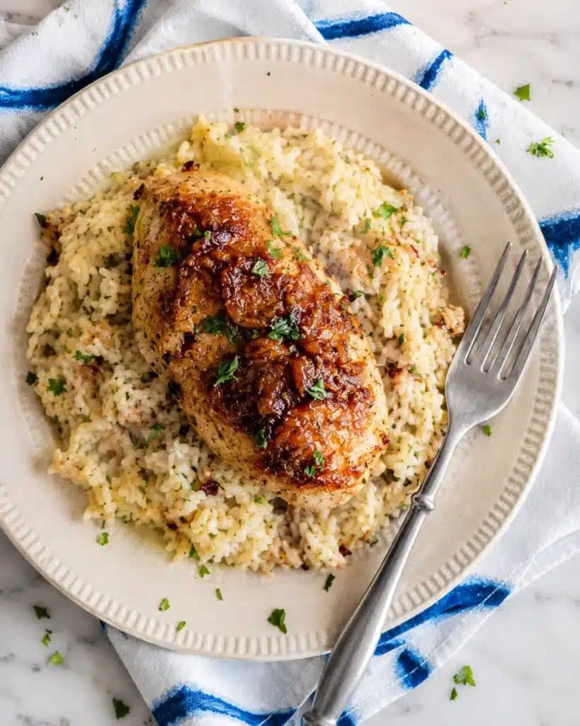 Served portion of chicken and rice on a beige plate with parsley garnish and fork on the side