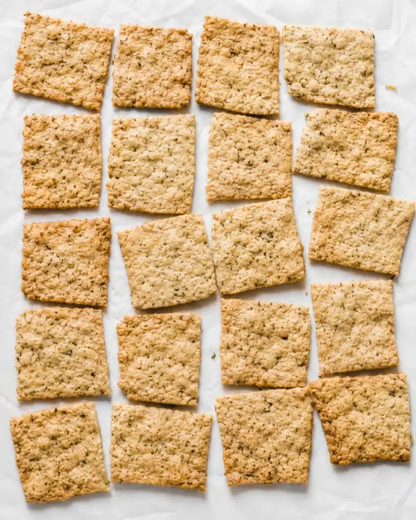 freshly baked square crackers arranged on parchment paper in a neat grid pattern