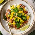 overhead spicy mango chicken bowl with fresh ingredients and herbs