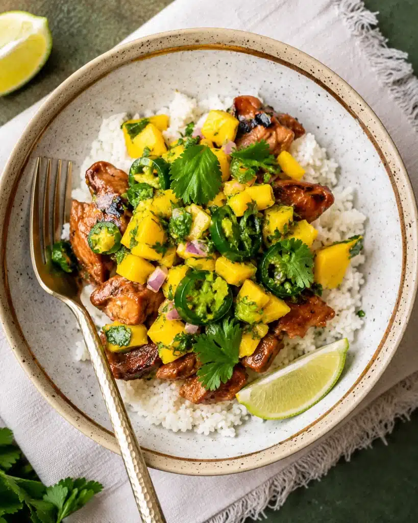 overhead spicy mango chicken bowl with fresh ingredients and herbs