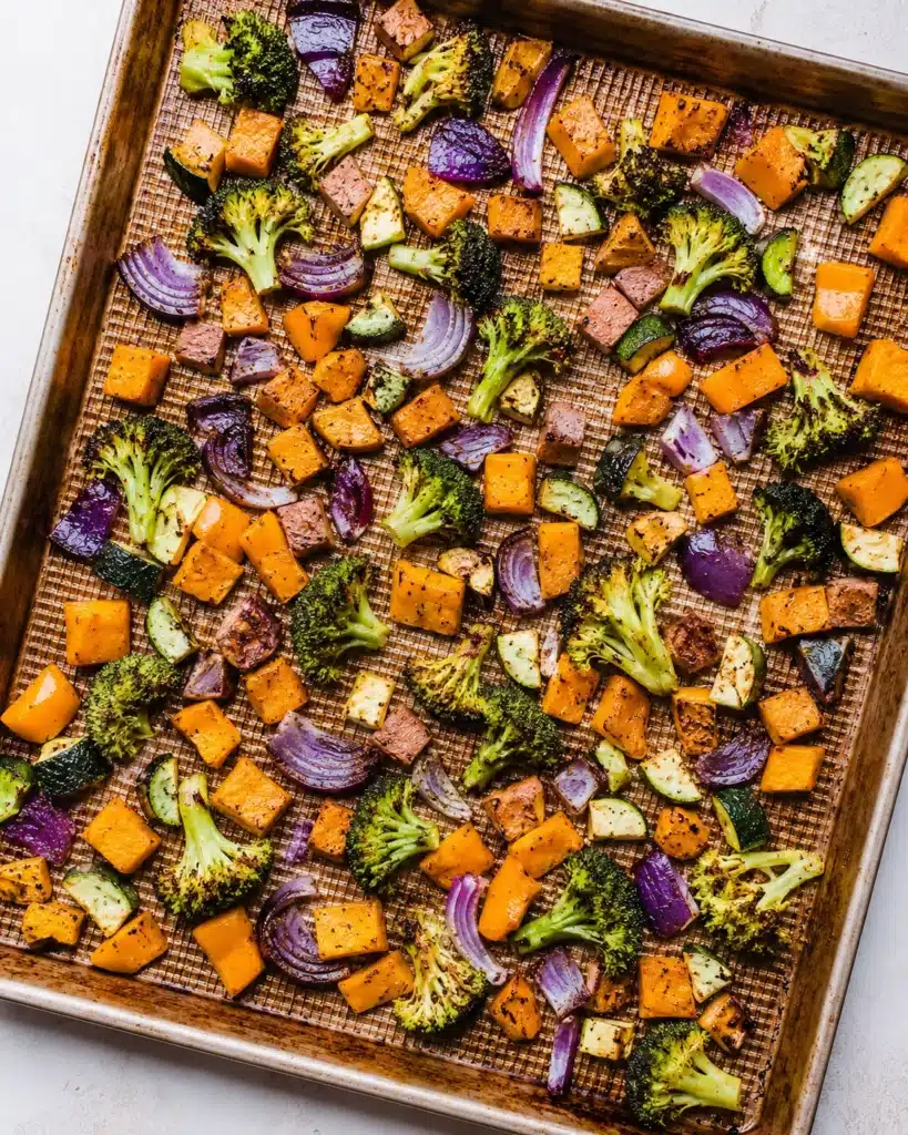 sheet pan filled with roasted vegetables including broccoli sweet potatoes and zucchini