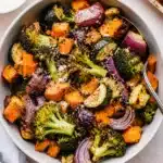 roasted vegetable bowl served with spoon and seasoning on top