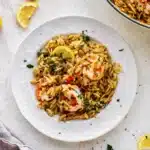 Plate of shrimp orzo garnished with parsley and a slice of lemon