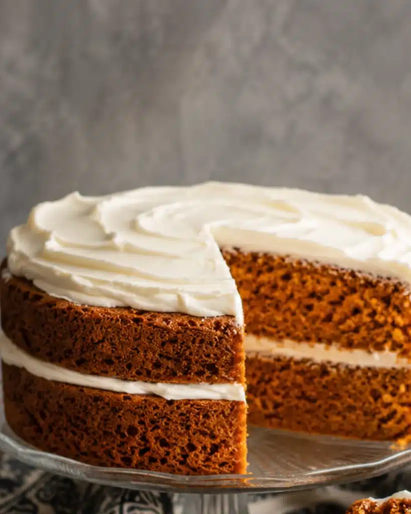 layered homemade cake on glass stand with creamy frosting