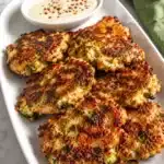 Plate of homemade fritters served with dipping sauce and fresh salad on the side