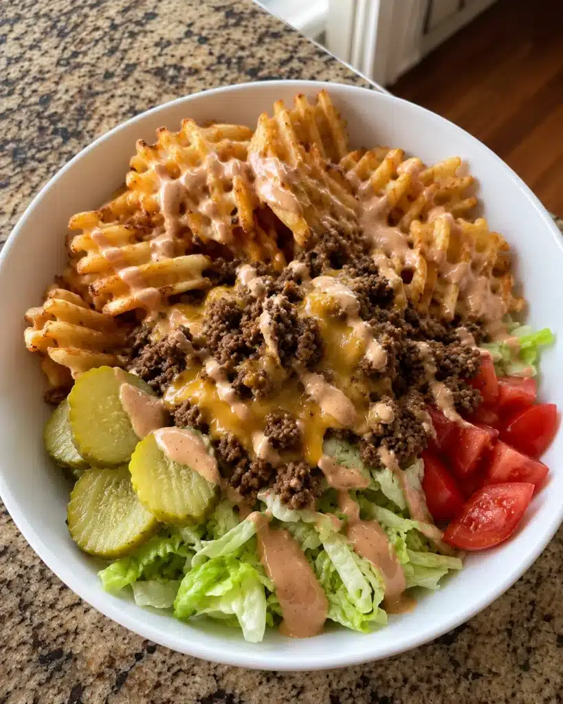 Cheesy beef bowl with waffle fries, pickles, tomatoes, lettuce, and creamy sauce
