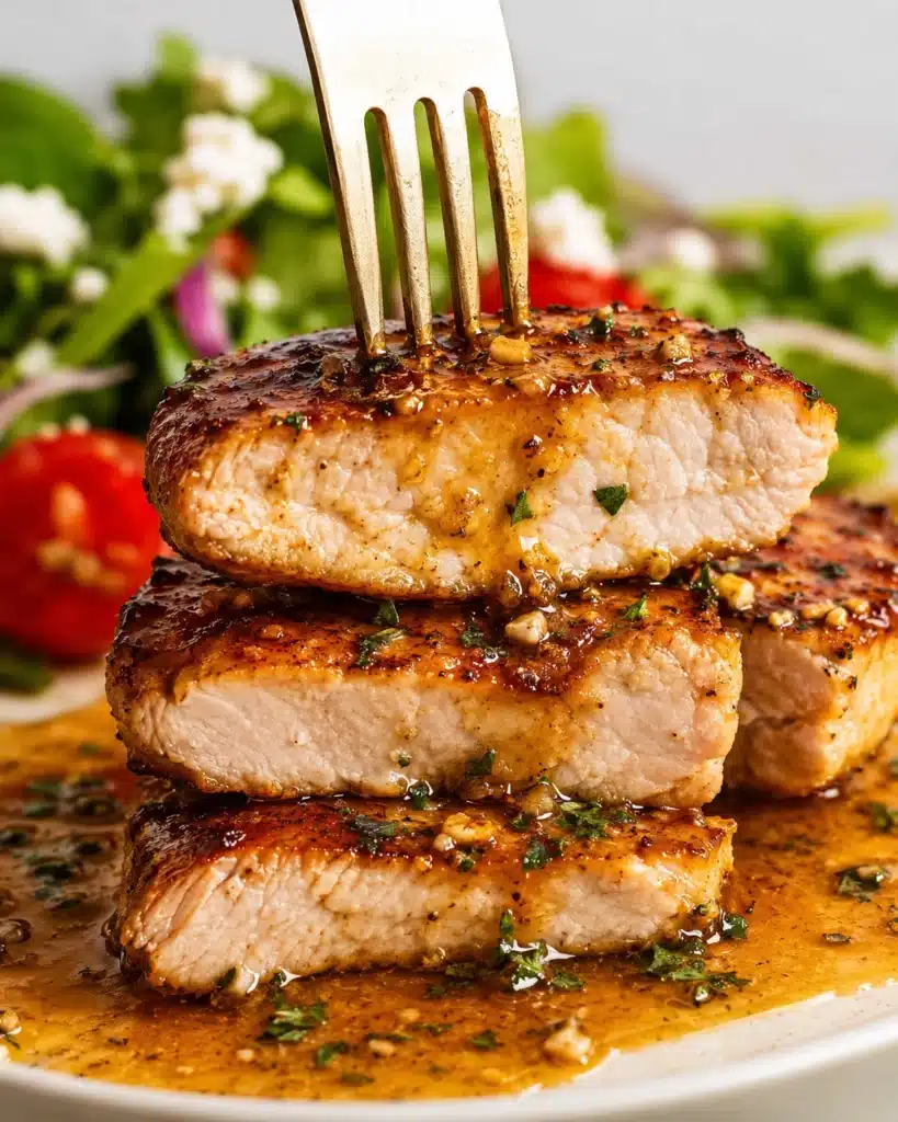Stacked slices of chicken breast with fork showing tender inside and garlic sauce on top