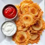 Golden baked onion slices with crispy parmesan edges served with ketchup and creamy dip