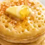 honey being poured over butter on a crumpet showing glossy texture and soft interior