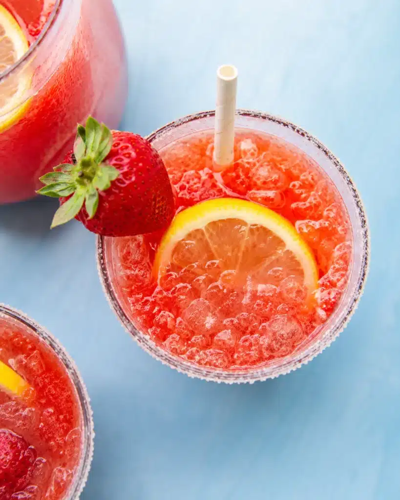 Top view of strawberry lemonade with ice, lemon slice, and sugared rim glass