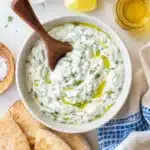 Creamy yogurt cucumber dip with olive oil and fresh dill served with warm pita bread
