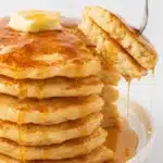 Thick fluffy pancakes cooking on a black nonstick griddle with bubbles on the surface