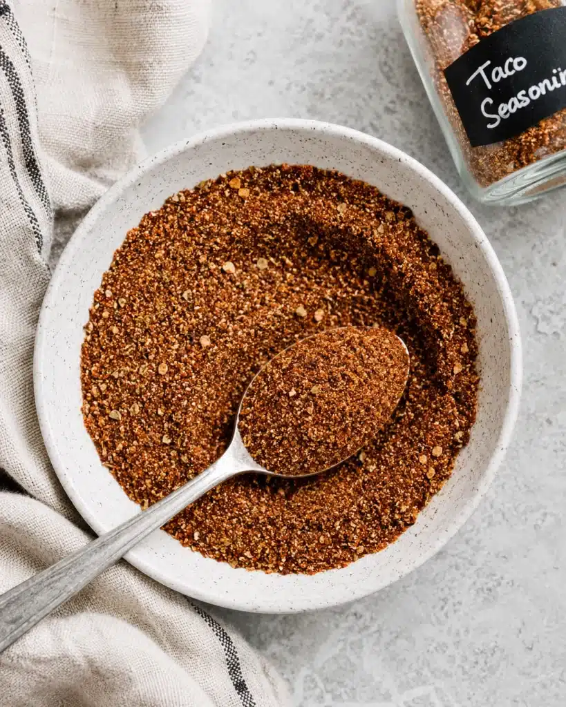 close up of taco seasoning blend in a white bowl with a spoon
